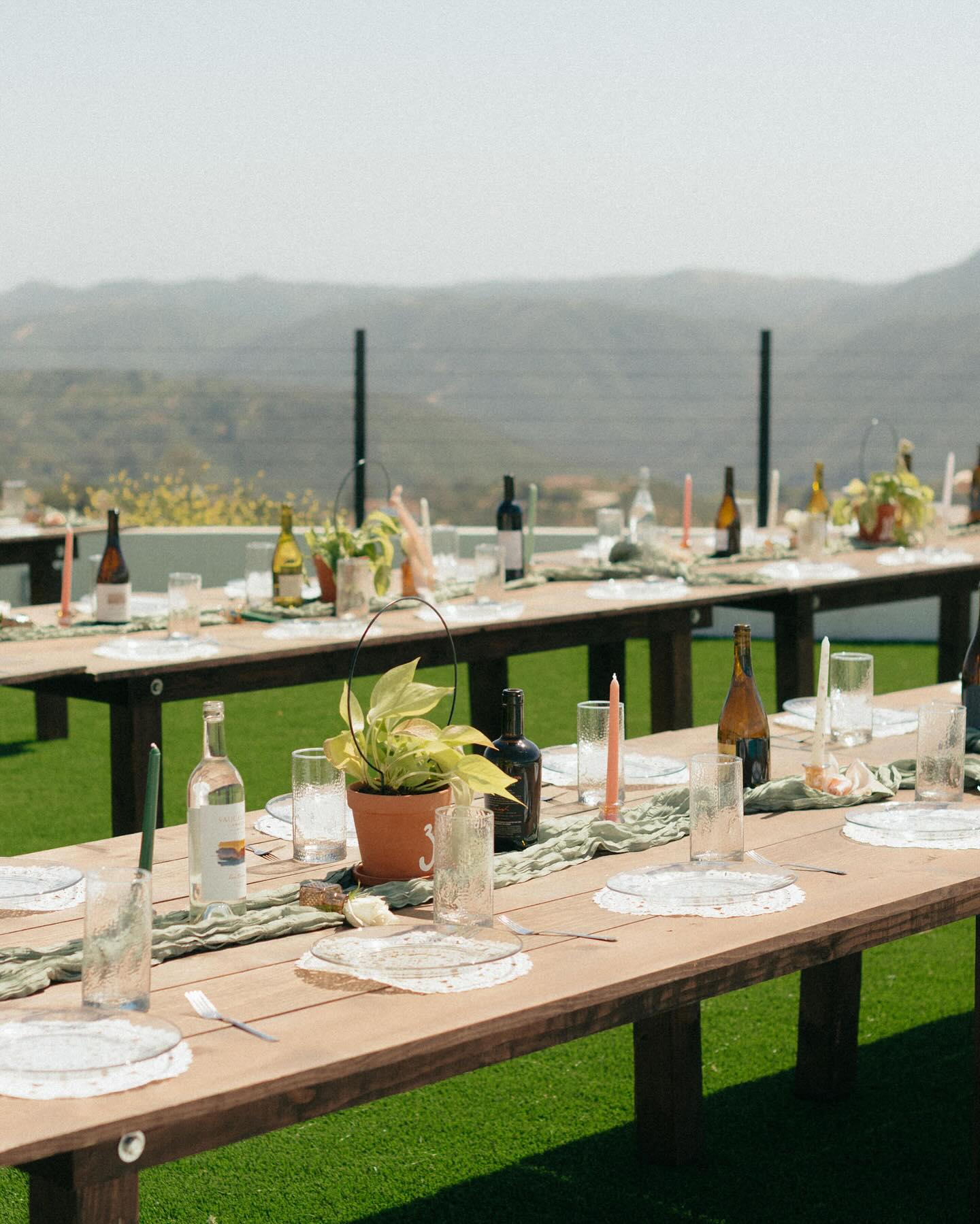 Outdoor reception tablescape with sage runners, candles, and mountain views