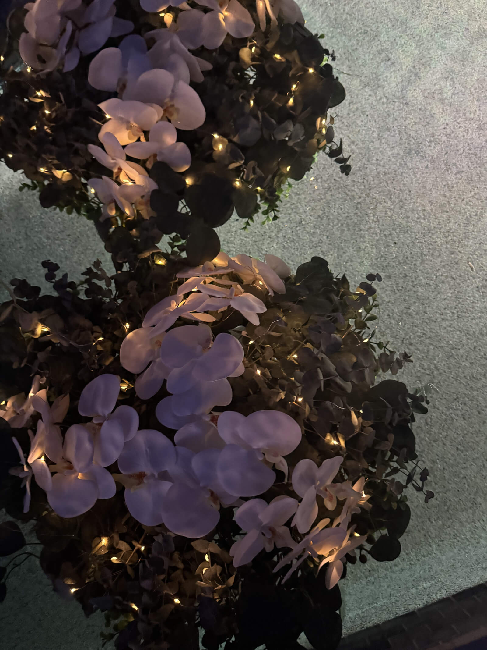 Floating bouquets glowing on water at an evening wedding reception